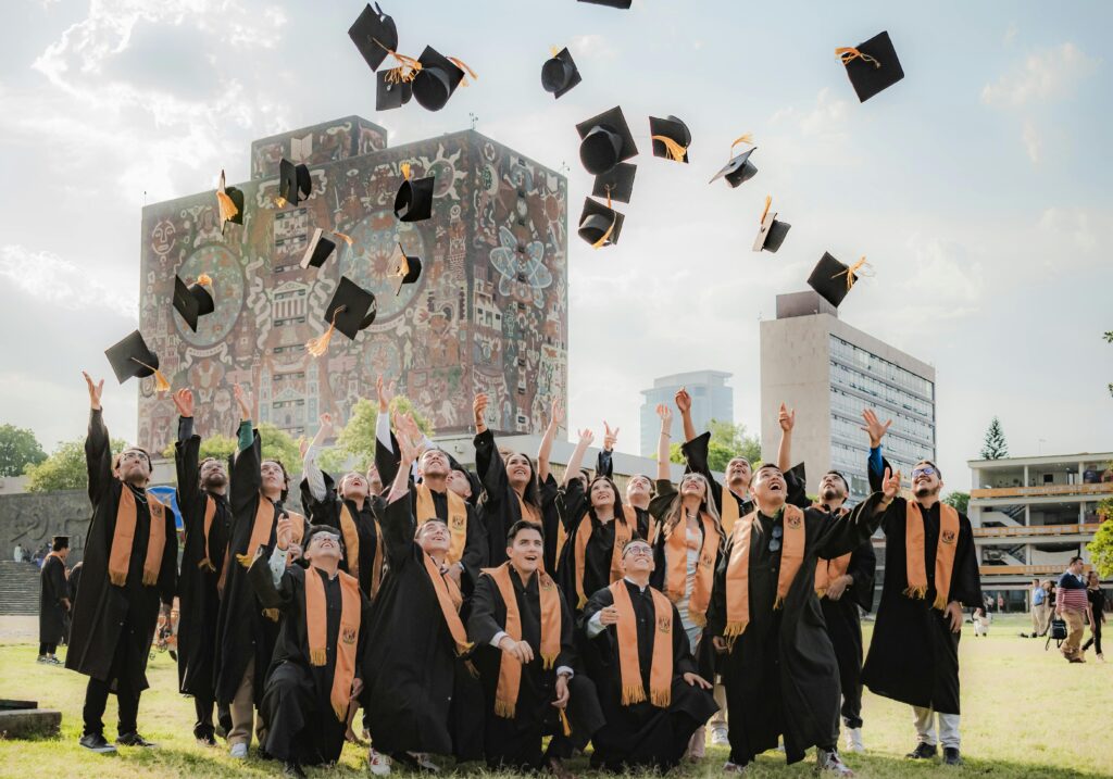 Graduates joyfully toss hats in the air by UNAM Central Library in Mexico City.